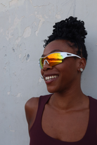 Woman wearing reflective sports sunglasses against a textured wall