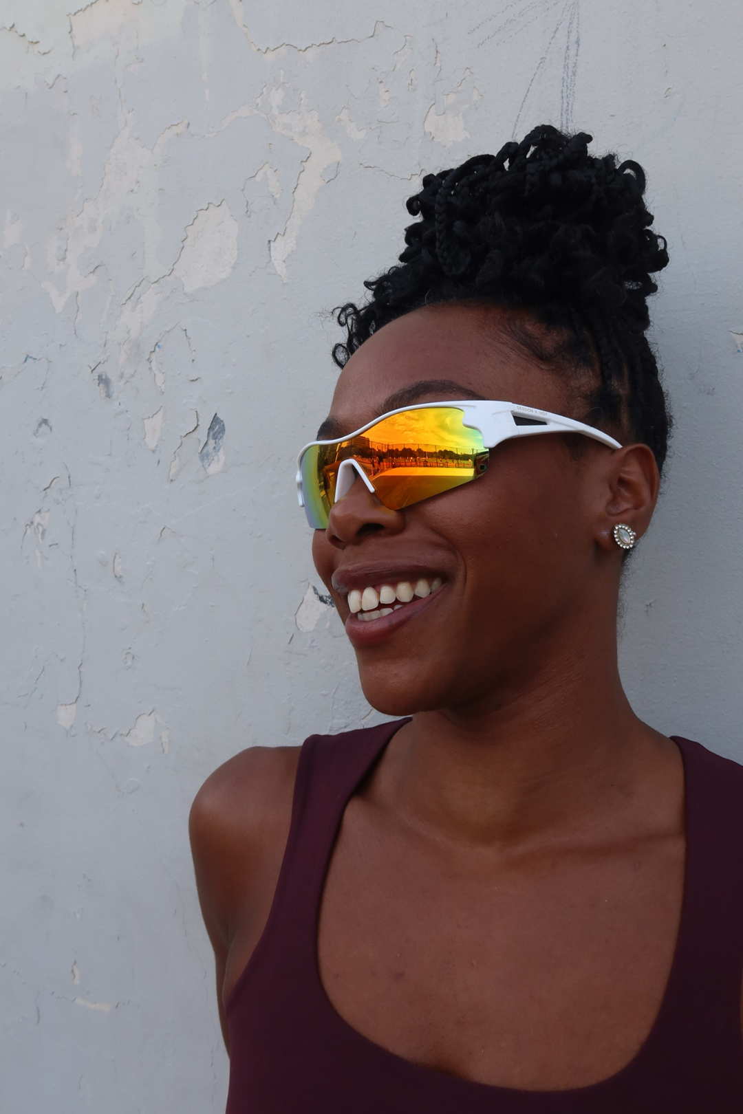 Woman wearing reflective sports sunglasses against a textured wall