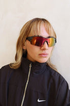 Person wearing reflective sunglasses and a black Nike jacket against a plain background