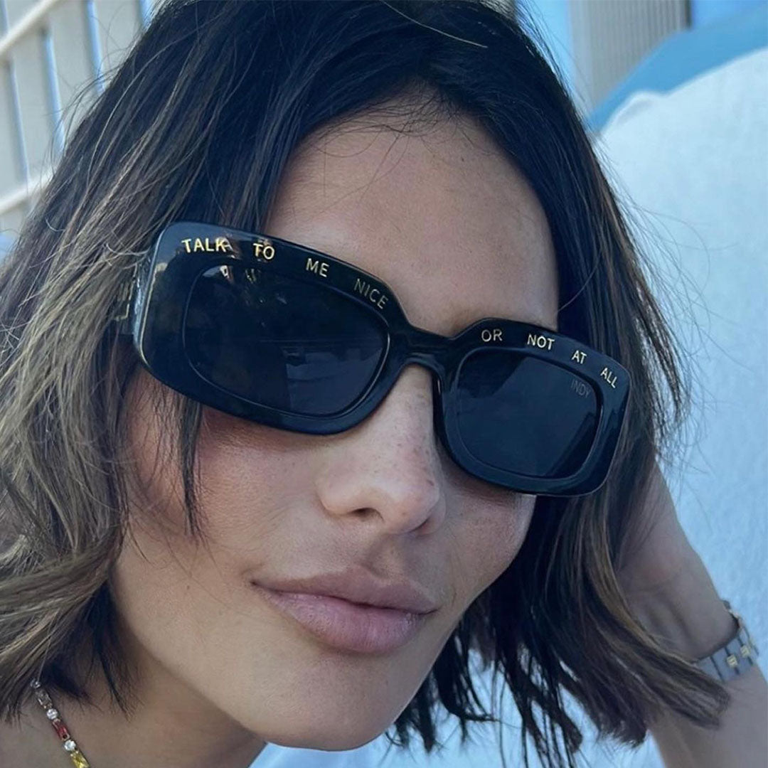 a model wears black sunglasses with gold wording