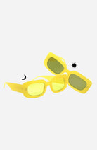 Yellow sunglasses with green lenses on a white background