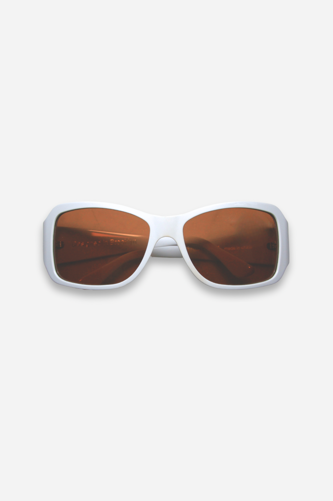 Sunglasses with white frame and brown lenses on a light gray background
