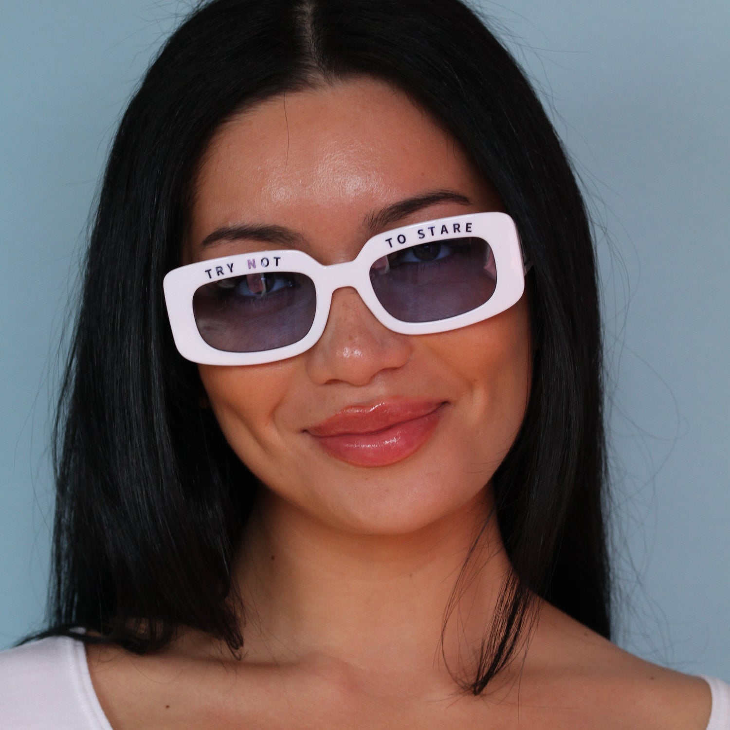 a girl with brown hair smiling wearing white sunglasses