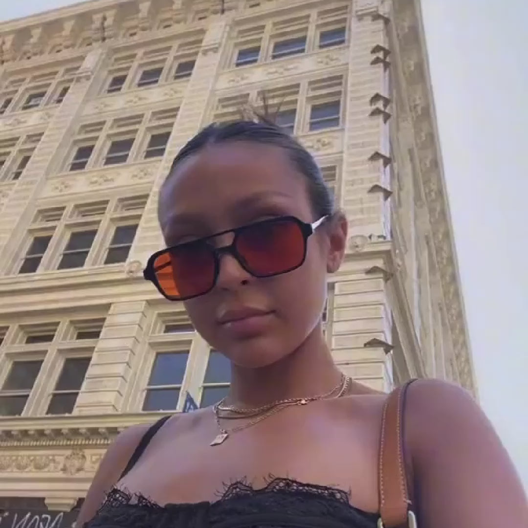 a girl wearing orange sunglasses in the street