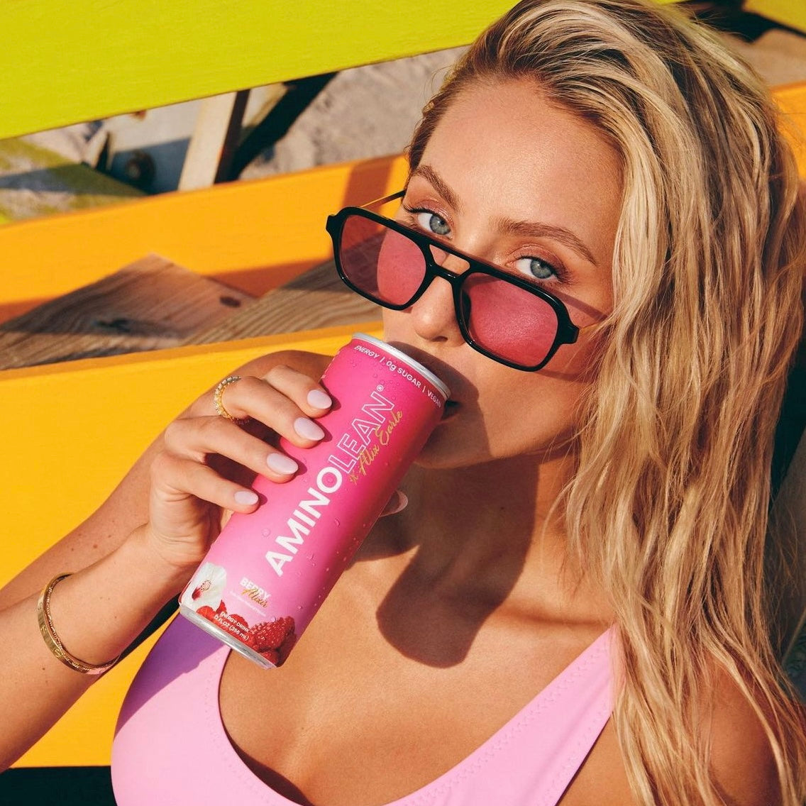 alix earle wearing pink sunglasses drinking a beverage 